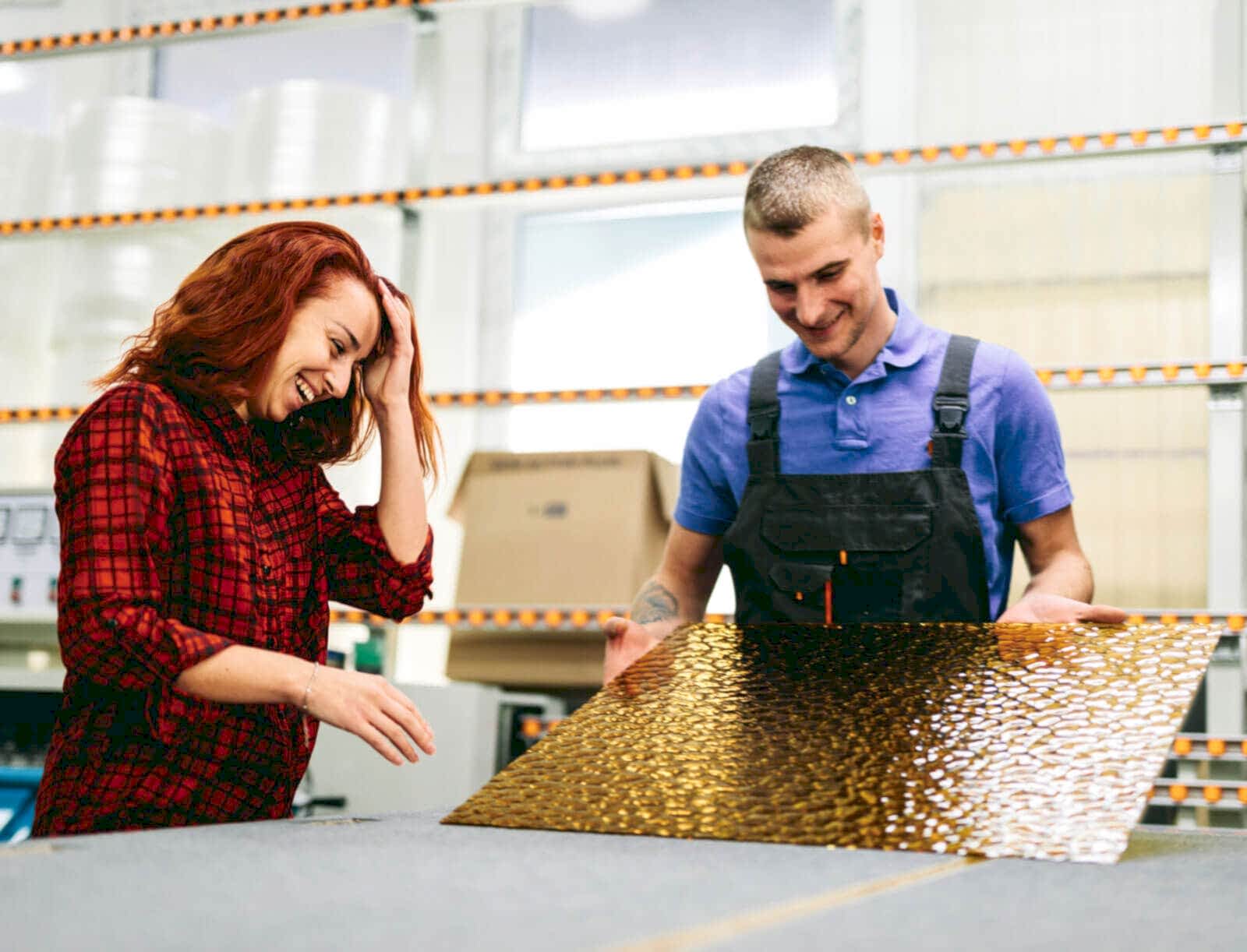 Man and woman working on glass pane in glazier